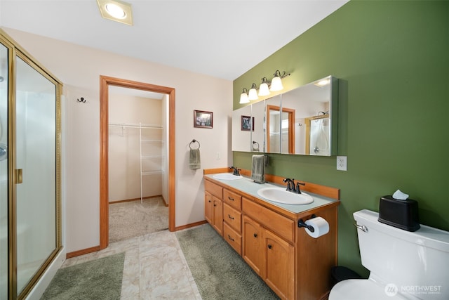 bathroom with a stall shower, a sink, toilet, and double vanity