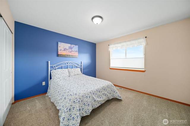 bedroom featuring a closet, carpet flooring, visible vents, and baseboards