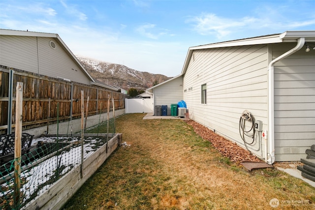 view of home's exterior featuring cooling unit, a fenced backyard, a mountain view, a yard, and a vegetable garden