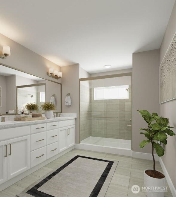 bathroom with double vanity, a stall shower, baseboards, and a sink