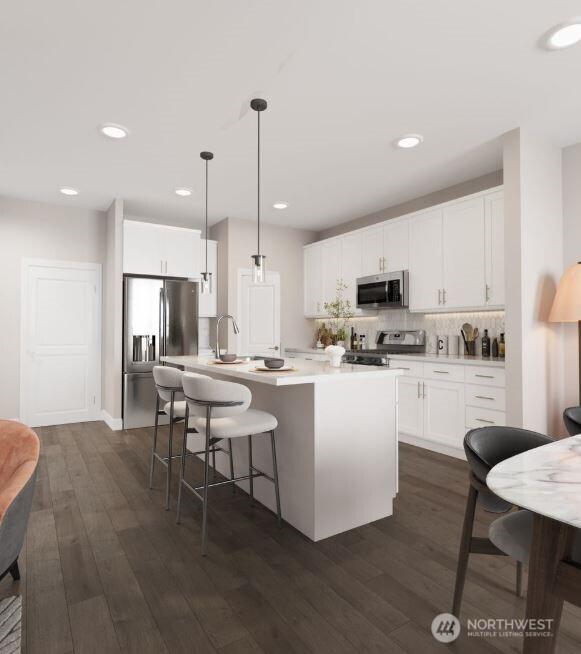 kitchen featuring light countertops, appliances with stainless steel finishes, white cabinetry, and pendant lighting