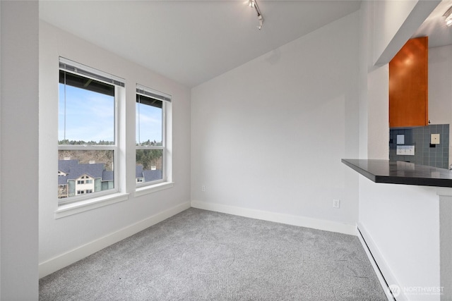 unfurnished dining area with lofted ceiling, track lighting, baseboards, and carpet flooring