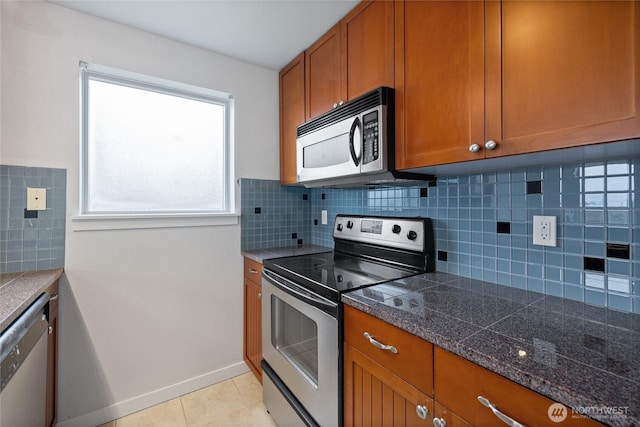 kitchen featuring stainless steel appliances, brown cabinetry, light tile patterned flooring, and decorative backsplash