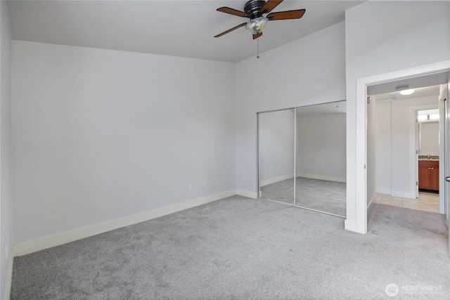 unfurnished bedroom featuring light carpet, a ceiling fan, baseboards, and a closet