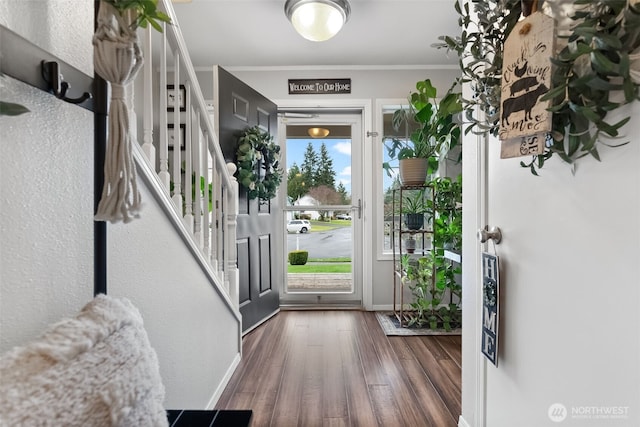 foyer featuring stairs, baseboards, wood finished floors, and crown molding