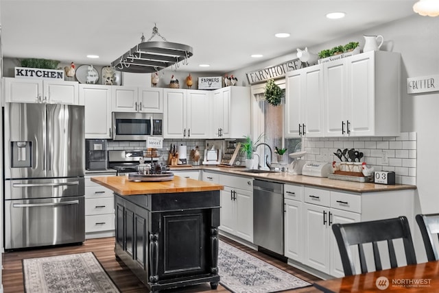 kitchen featuring butcher block counters, appliances with stainless steel finishes, white cabinets, and a sink