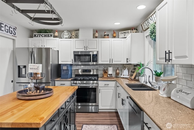 kitchen with stainless steel appliances, butcher block countertops, a sink, and white cabinets