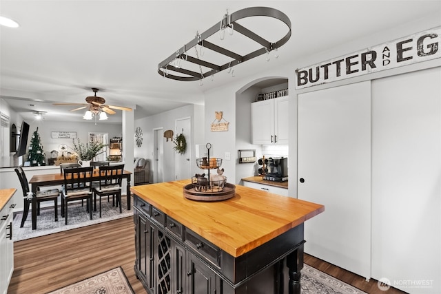 kitchen with butcher block counters, wood finished floors, white cabinetry, a ceiling fan, and dark cabinetry