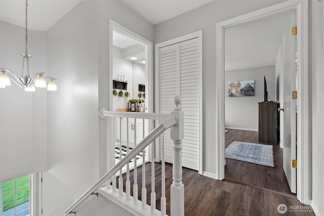 hallway with a chandelier, wood finished floors, an upstairs landing, and baseboards