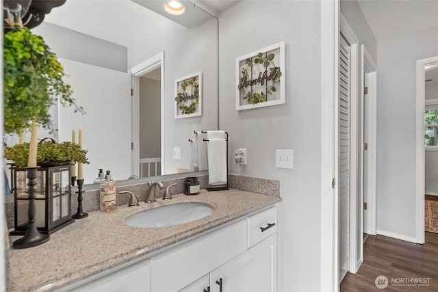 bathroom featuring baseboards, wood finished floors, and vanity