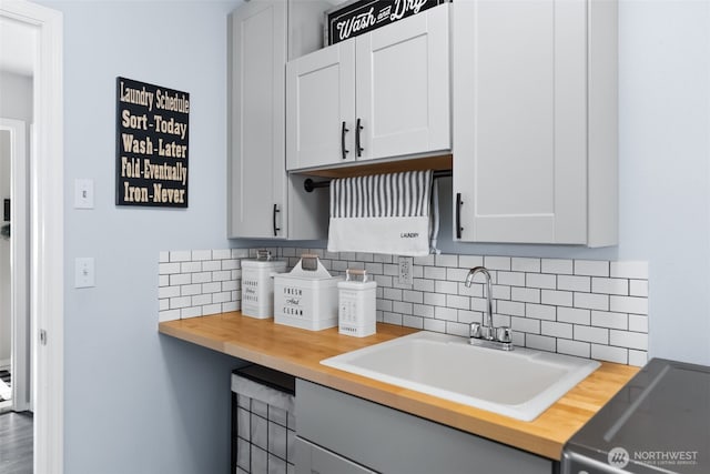 kitchen featuring electric range, a sink, gray cabinetry, wooden counters, and backsplash