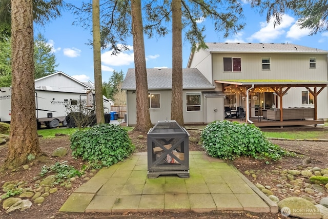 rear view of property with a deck and an outdoor living space with a fire pit