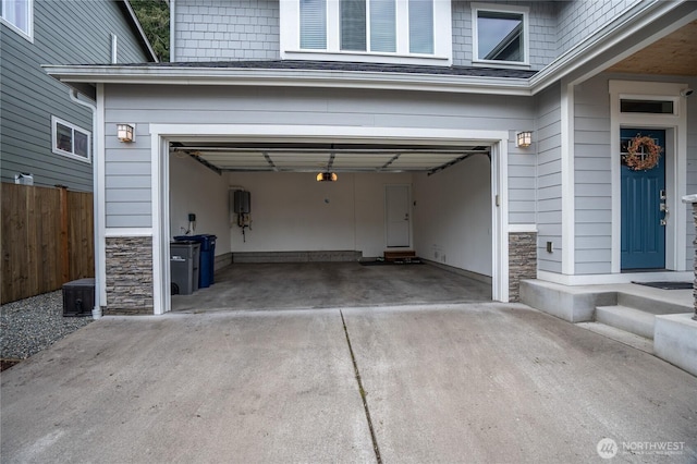 garage featuring fence and concrete driveway