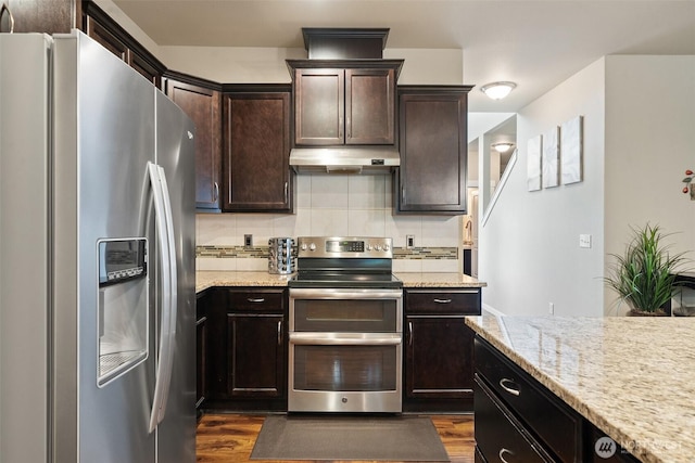 kitchen with under cabinet range hood, dark wood finished floors, stainless steel appliances, and backsplash