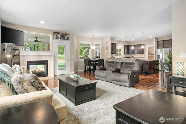 living room with recessed lighting, a tiled fireplace, and wood finished floors