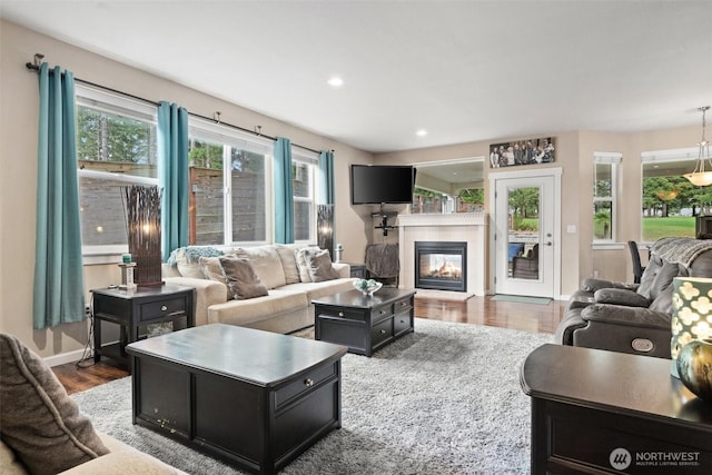 living area with recessed lighting, baseboards, a tiled fireplace, and wood finished floors