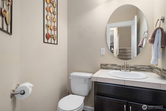 bathroom with backsplash, toilet, and vanity