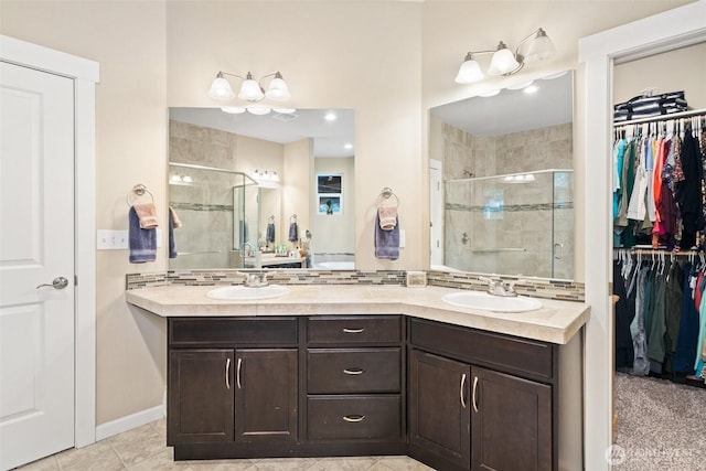 bathroom featuring a walk in closet, a sink, and a shower stall