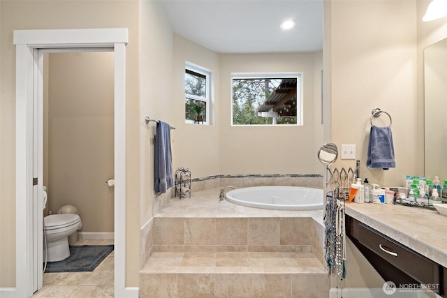 full bath featuring a garden tub, toilet, vanity, baseboards, and tile patterned floors