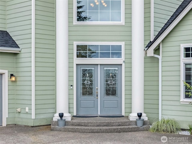 view of exterior entry with roof with shingles