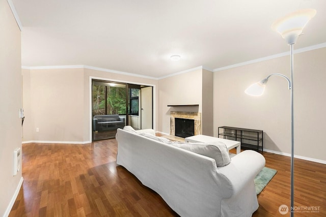 living area with baseboards, wood finished floors, a high end fireplace, and crown molding