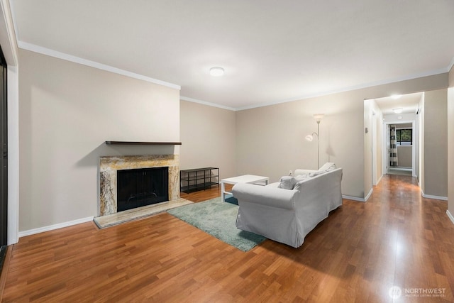 living area featuring baseboards, a fireplace, wood finished floors, and crown molding