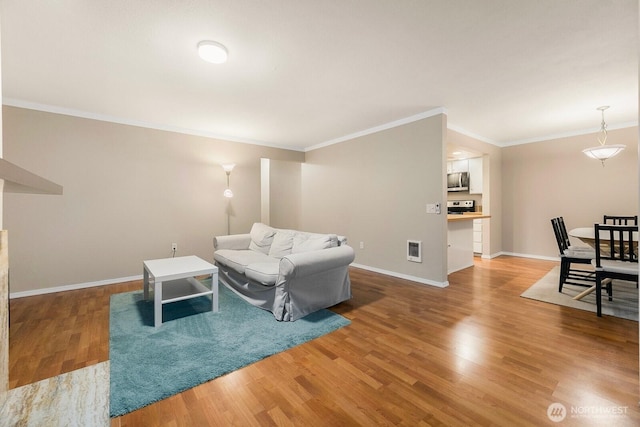 living room featuring crown molding, wood finished floors, visible vents, and baseboards