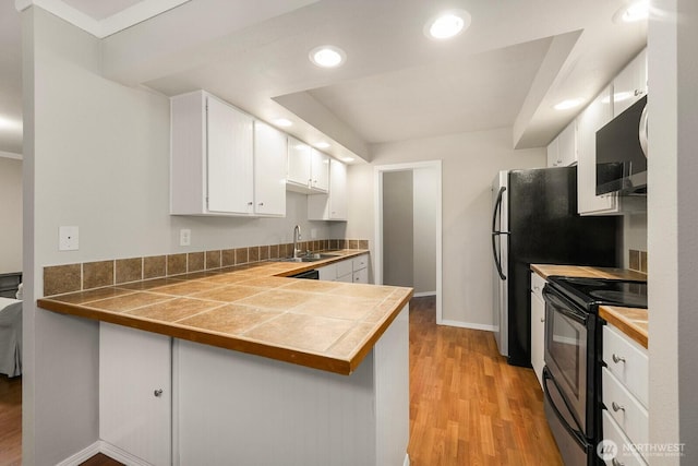 kitchen featuring electric stove, tile countertops, white cabinetry, a sink, and light wood-type flooring