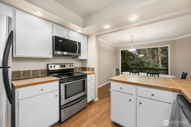 kitchen featuring stainless steel appliances, crown molding, light wood-style floors, white cabinetry, and pendant lighting