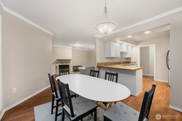 dining area featuring recessed lighting, a fireplace, wood finished floors, baseboards, and crown molding