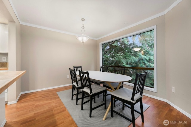 dining area with ornamental molding, baseboards, and wood finished floors