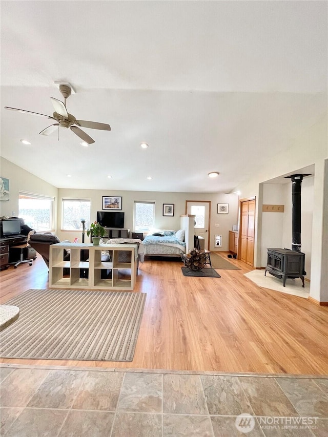 bedroom with light wood-type flooring, a wood stove, multiple windows, and recessed lighting