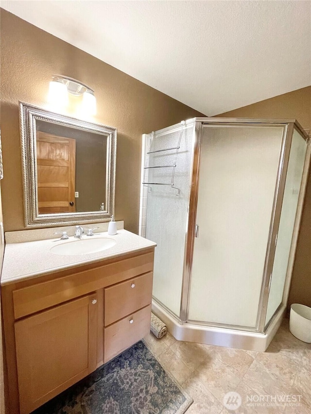 full bath with lofted ceiling, a textured ceiling, tile patterned flooring, vanity, and a stall shower