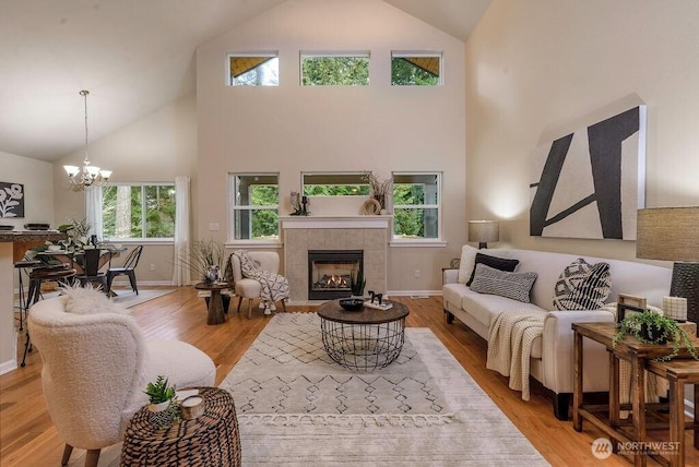 living area with baseboards, a fireplace, a chandelier, and wood finished floors