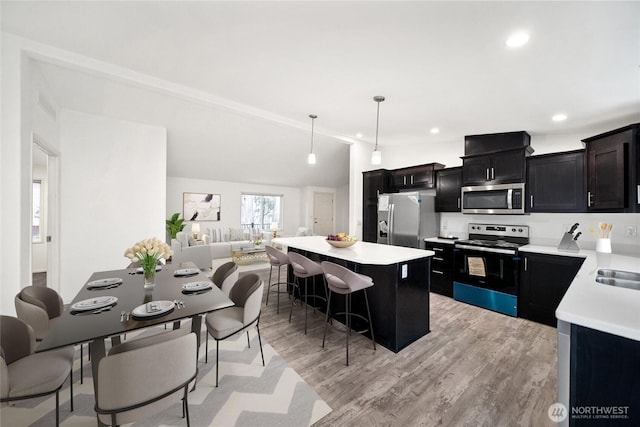 kitchen featuring open floor plan, appliances with stainless steel finishes, light countertops, and pendant lighting