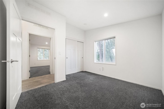 unfurnished bedroom with recessed lighting, visible vents, baseboards, a closet, and dark colored carpet