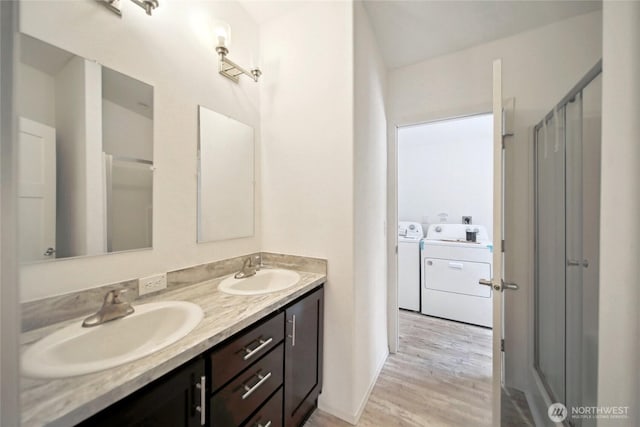 full bath with wood finished floors, double vanity, washing machine and dryer, and a sink