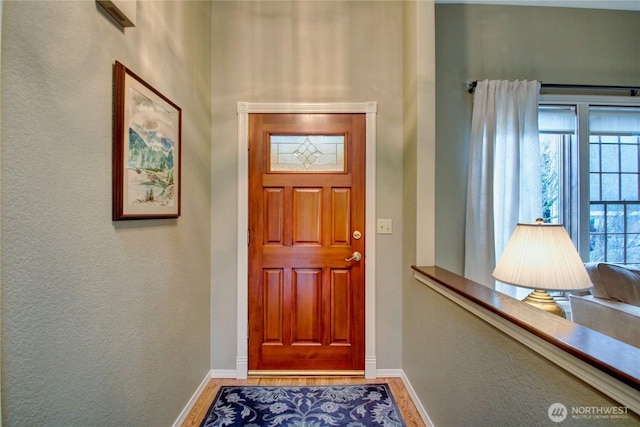 entryway with baseboards, wood finished floors, and a textured wall