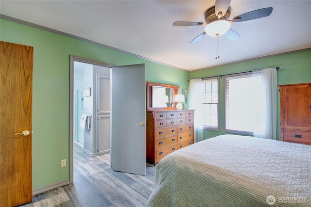 bedroom with light wood-style flooring, a ceiling fan, baseboards, ornamental molding, and ensuite bath