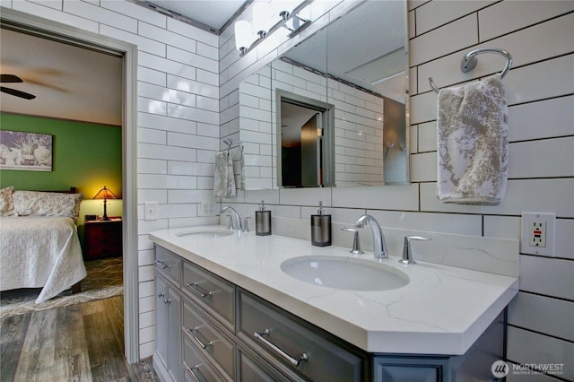 bathroom featuring ensuite bathroom, wood finished floors, backsplash, and a sink