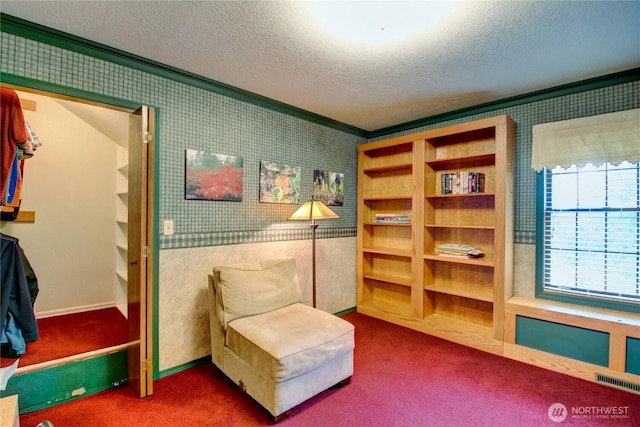 living area with wallpapered walls, a textured ceiling, visible vents, and crown molding