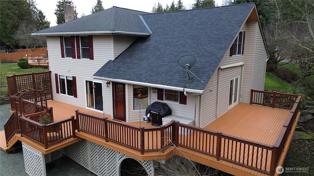 rear view of house with a shingled roof, a chimney, and a wooden deck