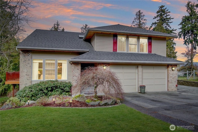 split level home featuring a garage, concrete driveway, roof with shingles, and a yard