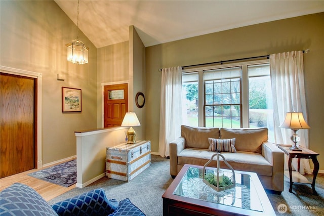 living area featuring a notable chandelier, high vaulted ceiling, wood finished floors, and baseboards