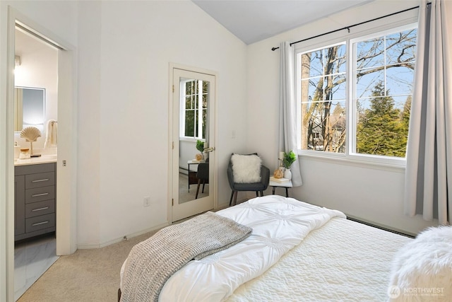 bedroom with light colored carpet, lofted ceiling, multiple windows, and ensuite bathroom