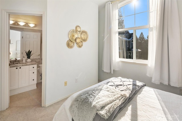 bedroom with light colored carpet, a sink, and ensuite bath