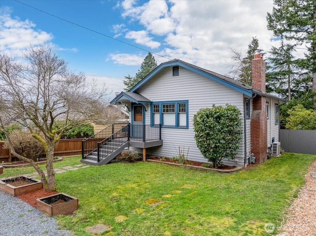 view of front of property featuring central AC, fence, a front yard, a garden, and a chimney