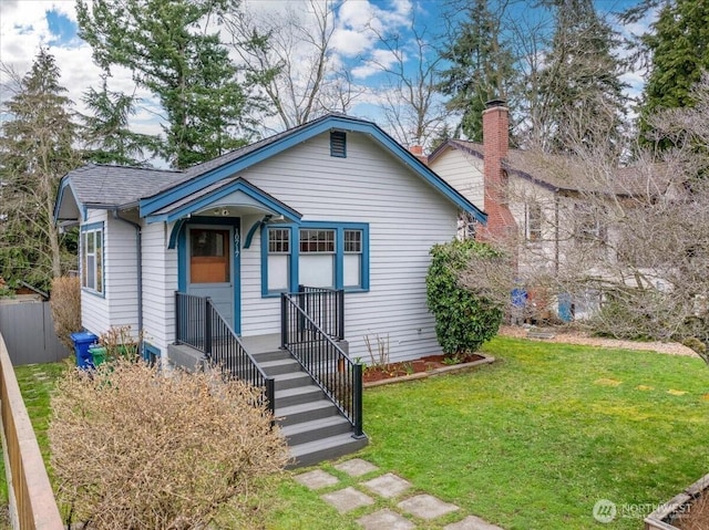 bungalow-style home with a front lawn, fence, a chimney, and a shingled roof