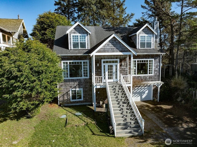 shingle-style home with french doors, stairway, a front yard, a garage, and driveway