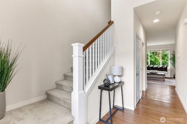 stairway featuring recessed lighting, wood finished floors, and baseboards